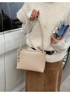 Detail of a creamy beige leather underarm bag featuring a stylish silver metal ball chain
