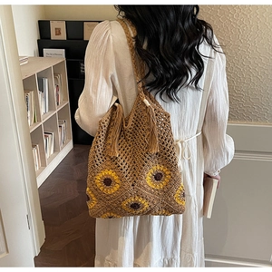 Detail of bohemian woven tote bag with sunflower pattern and fringe tassels for beach vacations