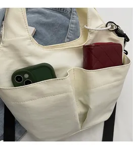 Dettaglio della borsa tote crema con tasche esterne per telefono e portafoglio rosso