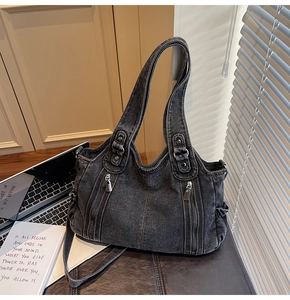 Detail of dark gray washed denim tote bag featuring dual front zipper pockets and leather base