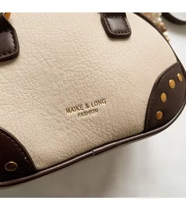Detail of lychee pattern leather handbag with gold rivets and metallic logo print