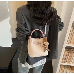 Detail view of pink and white bucket bag with metal twist lock and cute bunny charm on model