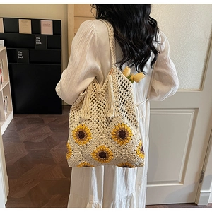 Detail of hand-woven beige tote bag with yellow sunflower patterns and fringe tassel decoration