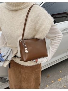 Detail of deep brown faux leather shoulder bag with silver moon charm and metallic chain