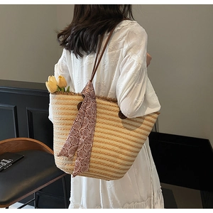 Detail of striped woven straw tote with brown button accent and red paisley silk scarf