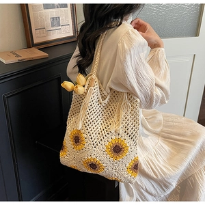 Detail of hand-crocheted beige tote bag with yellow sunflower patterns and tassel