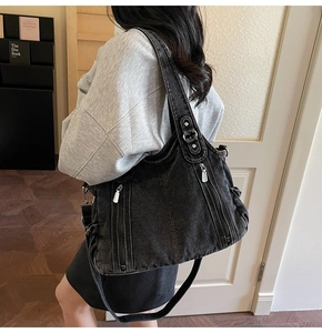 Close-up of vintage black denim tote bag featuring silver metal zippers and stud details