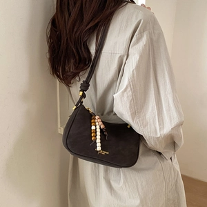 Detail of black suede half-moon bag with bohemian bead charms and knotted shoulder strap