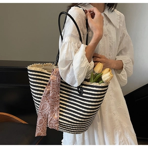 Close-up of black and white striped woven tote with fringe detail and paisley scarf
