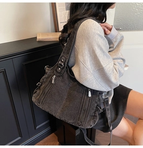 Detail of vintage black denim tote bag with side zippers and drawstring pockets on model