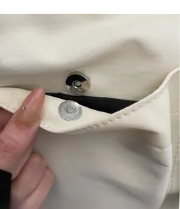 Dettaglio della fibbia magnetica circolare in metallo sulla borsa beige