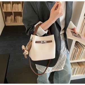 Detail of cream bucket bag with lychee grain leather, brown strap and bear charm