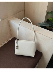 Detail of minimalist cream PU leather handbag with silver bean charm and metal chain