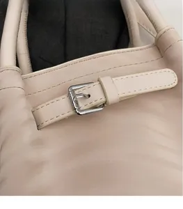 Gros plan d'un sac à main beige en cuir gaufré avec texture détaillée et boucle en métal argenté
