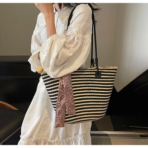 Detail of striped woven straw tote bag with red paisley silk scarf and fringe edges