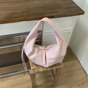 Detail of light pink moon-shaped hobo bag with drawstring tassels and soft pleated texture