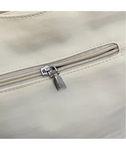 Dettaglio ravvicinato della cerniera in metallo argentato lucido sulla borsa beige