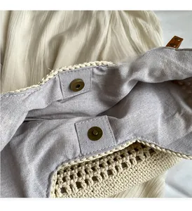 Detail of hand-woven straw tote with magnetic brass buckle and soft linen lining interior