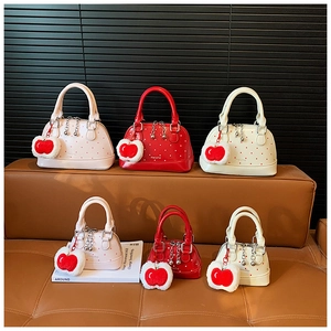 Detailed view of polka dot shell bags in red and pink with plush apple charms