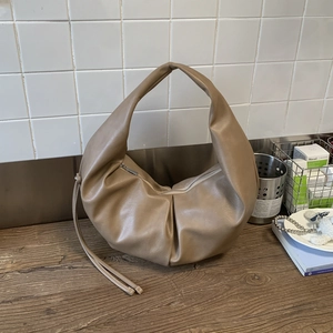Macro detail of khaki PU leather crescent bag with soft pleated design and top handle