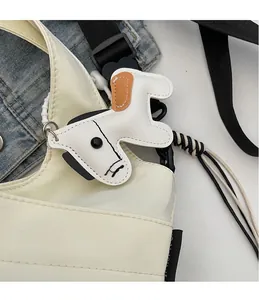 Dettaglio del ciondolo per borsa a forma di cane in pelle bianca con chiusura in metallo