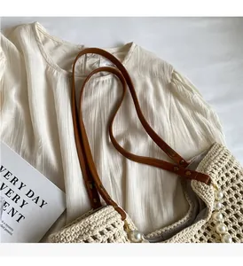 Detail of crochet straw tote with brown faux leather handles and white pearl decorations