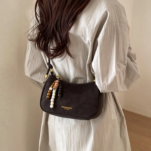 Detail of dark brown leather crescent bag with retro beads and gold fashion lettering