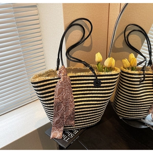Detail of black and white striped straw tote bag with fringe edge and decorative silk scarf