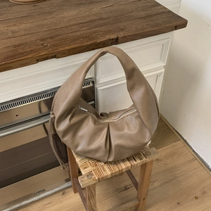 Detail shot of the cloud pleated leather hobo bag with smooth zipper on wood stool