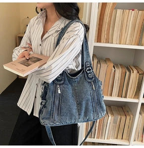 Detail of vintage washed blue denim tote bag with silver zipper accents and wide strap