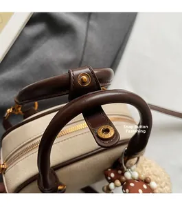 Detailed macro view of cream pebbled leather handbag with brown handles and gold snap buttons
