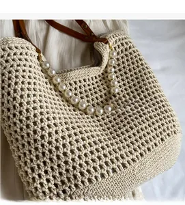 Close-up of beige crochet woven tote bag featuring large pearl beads and leather strap