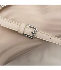 Détail de la bandoulière en cuir blanc cassé avec boucle en métal argenté poli et passant