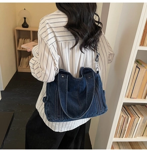 Detail view of deep blue denim tote bag with adjustable strap in a library setting