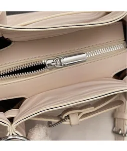 Gros plan sur la fermeture éclair argentée et les coutures d'un sac à main en cuir rose