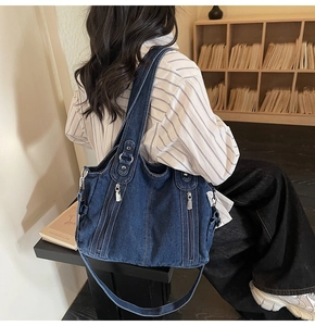 Deep blue denim tote bag detail featuring multiple silver zippers and adjustable strap