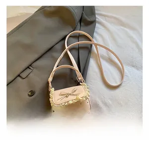 Detailed macro view of pink mini crossbody bag with delicate lace trim and metal bow accent