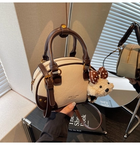 Close-up of cream white and brown leather handbag with cute plush dog charm