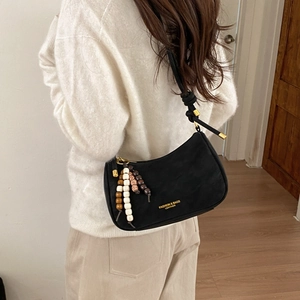 Detail of black leather hobo bag with knotted strap, gold hardware and beaded charm