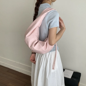 Close-up of light pink leather crescent bag showing soft texture and crossbody drape