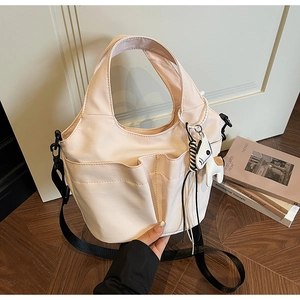 Dettaglio della borsa tote pieghettata beige con tasche frontali e ciondolo a cavallo