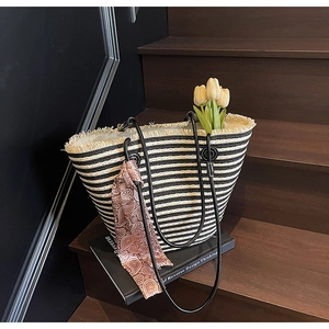 Detail of striped woven tote bag with black rope handles and decorative paisley silk scarf