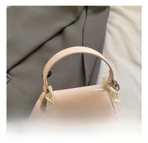 Pink mini square bag with lace trim and silver bow metal clasp shown on a grey blazer