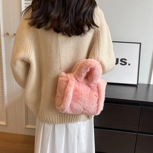 Sac seau rose en fausse fourrure avec bandoulière chaîne porté par un mannequin