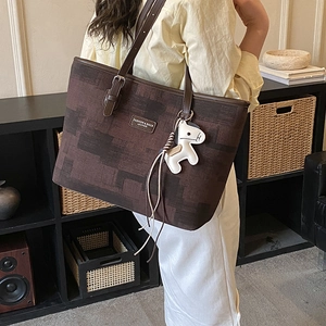 Detailed view of dark brown tote bag with geometric pattern and horse charm accessory