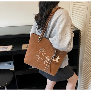 Detail of brown matte leather tote bag with white horse embroidery and a 3D horse charm