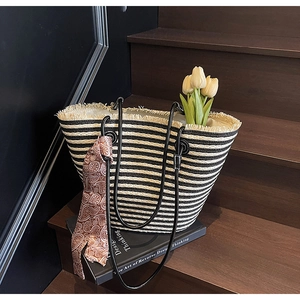 Detail of striped woven tote bag with beige fringe and decorative brown paisley scarf