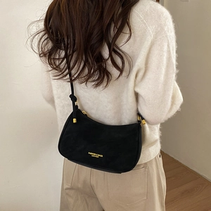 Detail view of black suede half-moon crossbody bag with gold hardware and fashion lettering