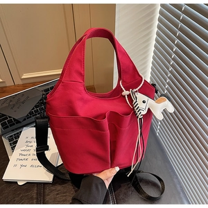 Dettaglio borsa tote rossa in tela con tasche, tracolla e ciondolo a forma di cane