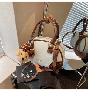 Detail of light blue Boston bag with leather texture, brand logo and plush bear charm